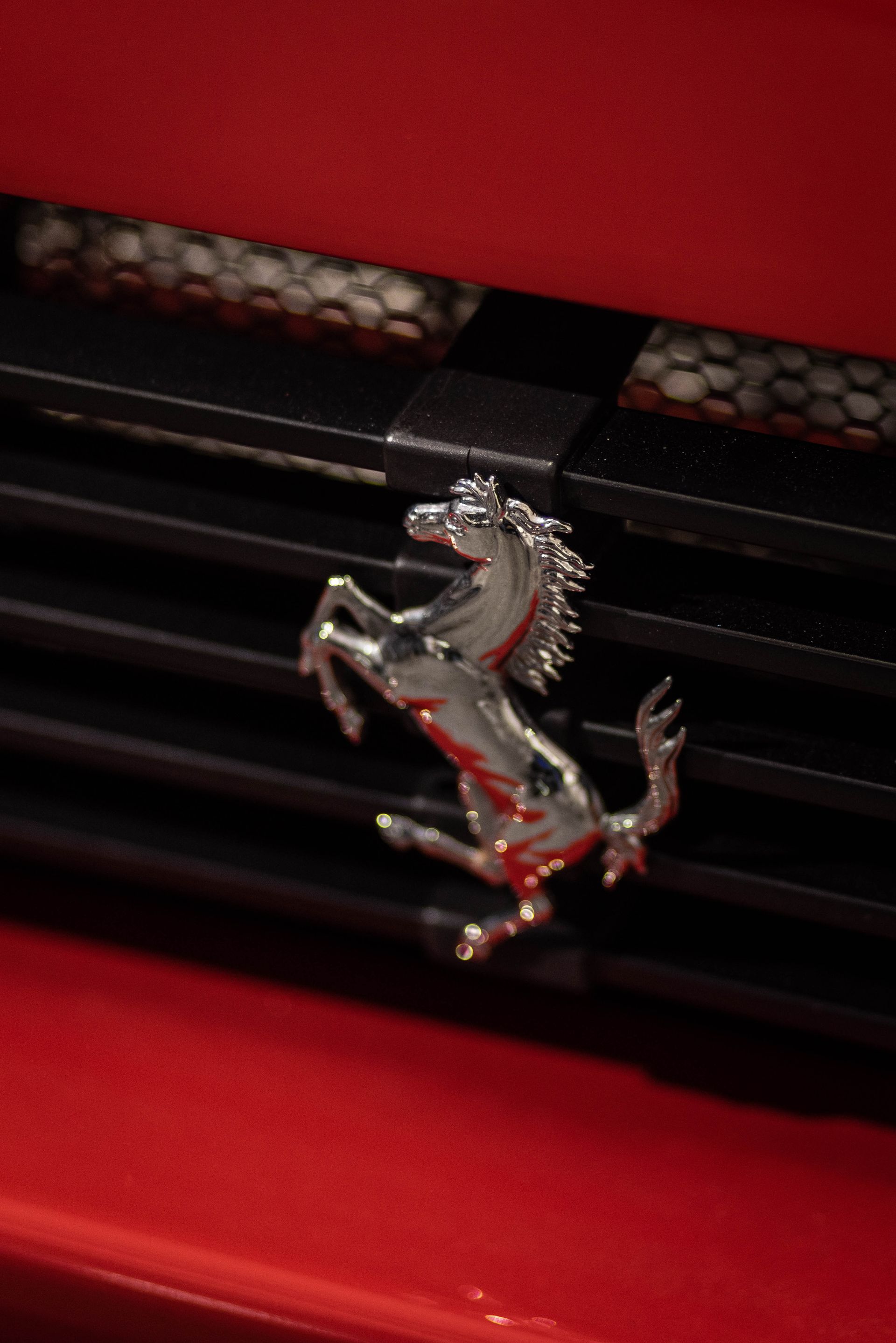 Ferrari hood emblem on a red car grille with black slats