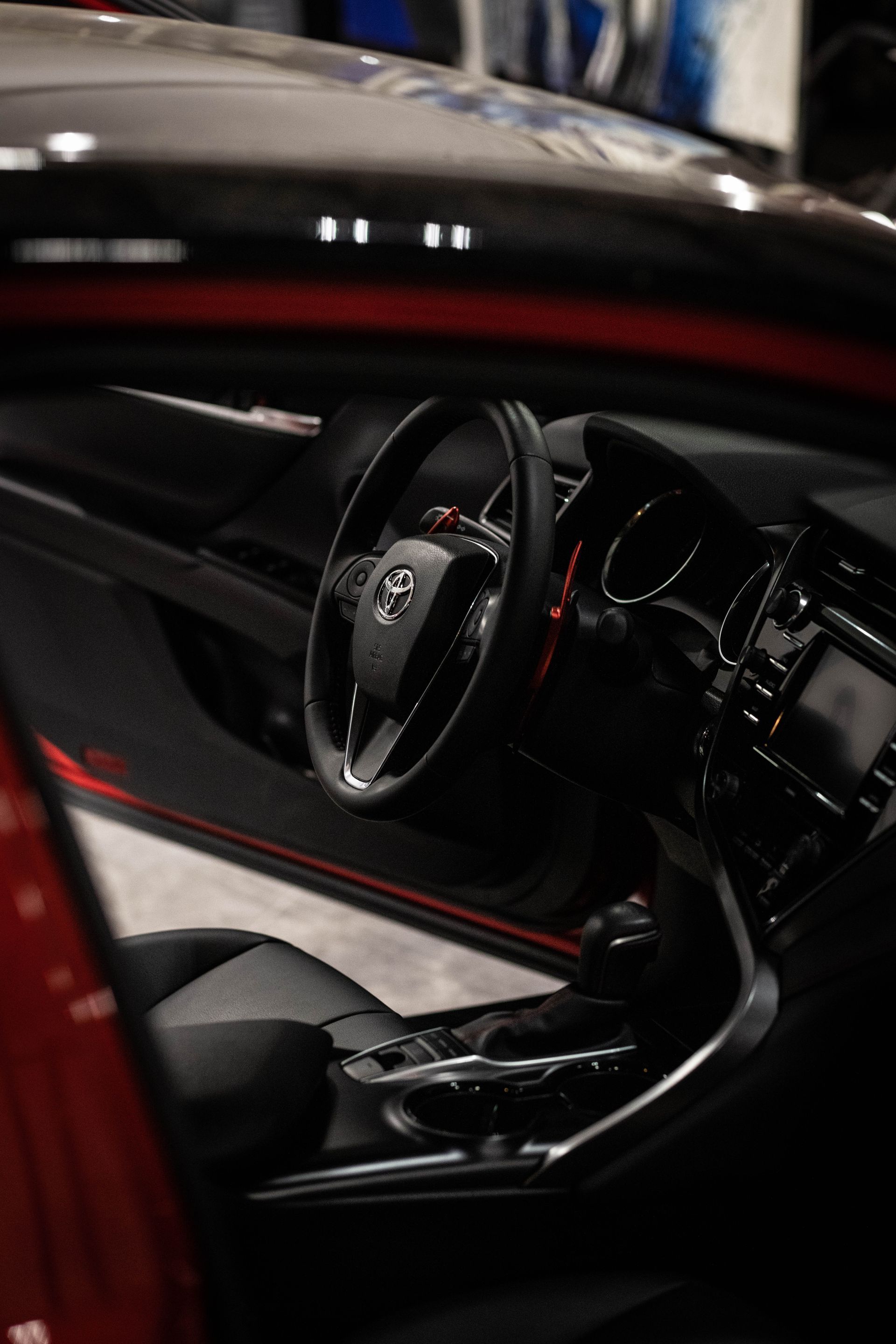 Close-up of a black sports car interior with red accents and a visible steering wheel