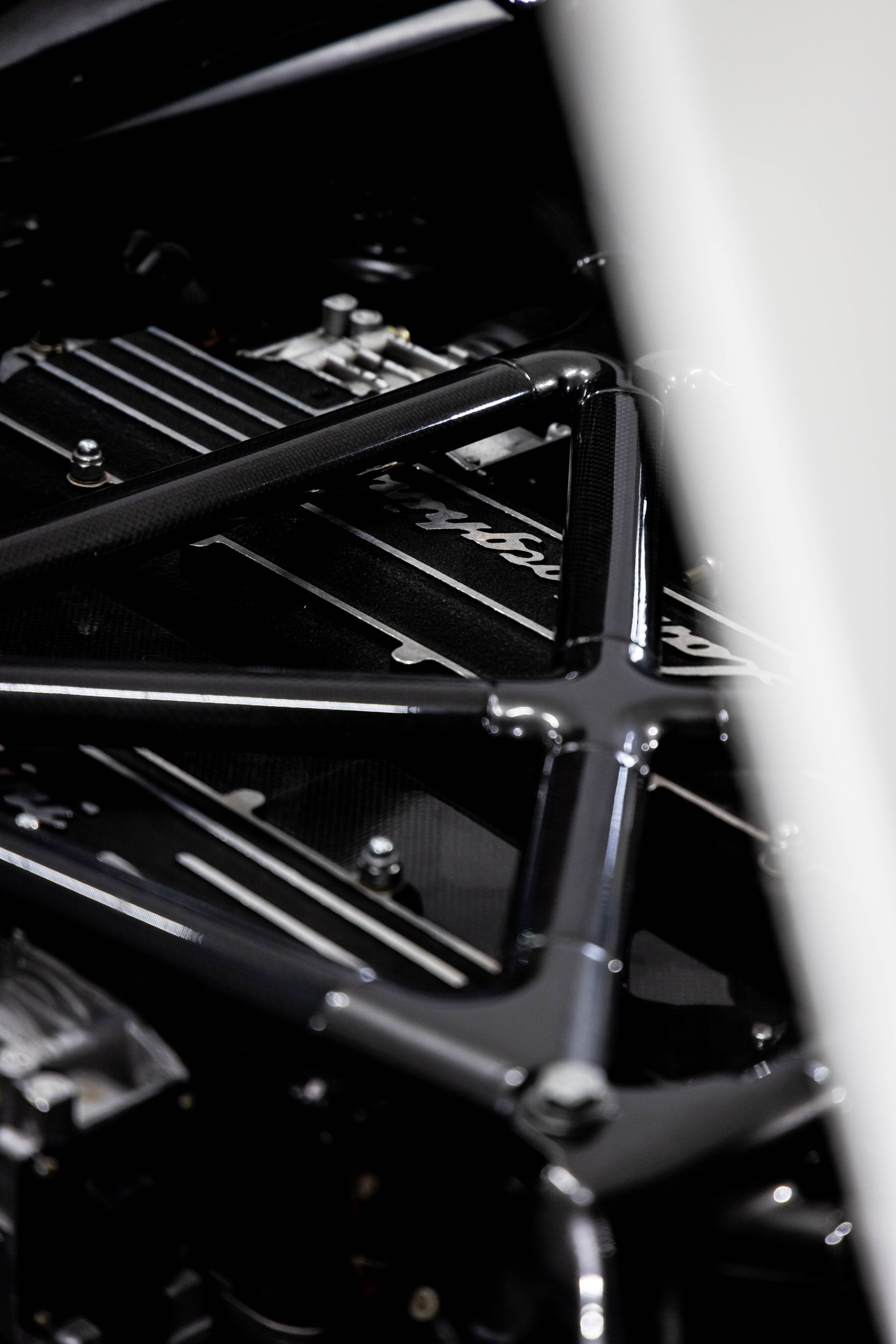 Close-up of a black metal lattice structure with glossy surfaces and a white vertical panel on the right