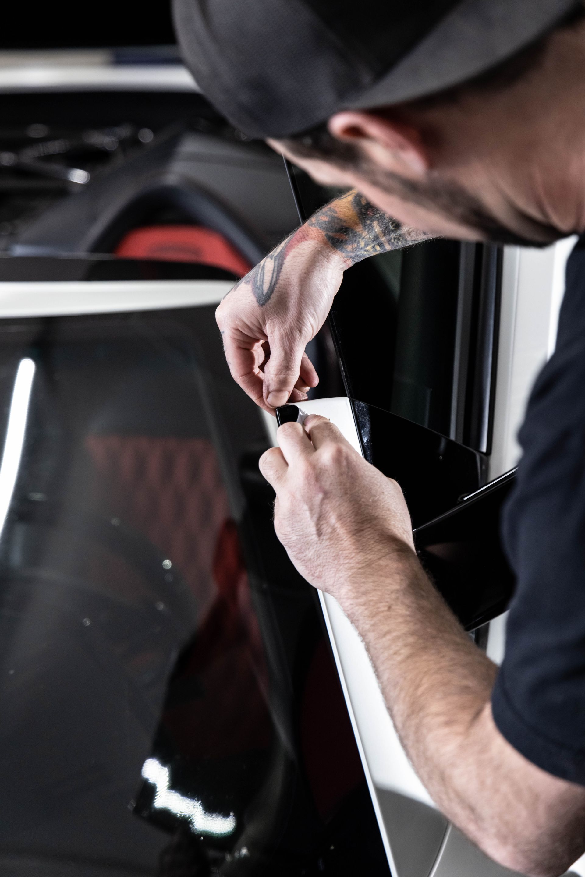 Worker applying vinyl film to a car window