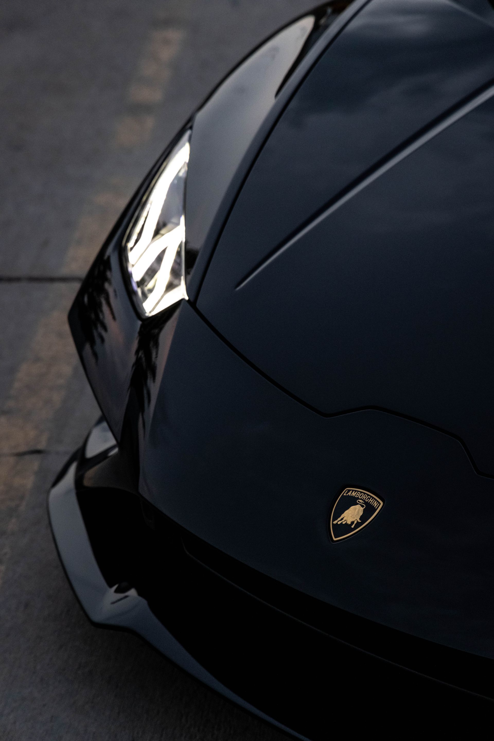 Front view of a black Lamborghini sports car with a silver emblem on the hood.