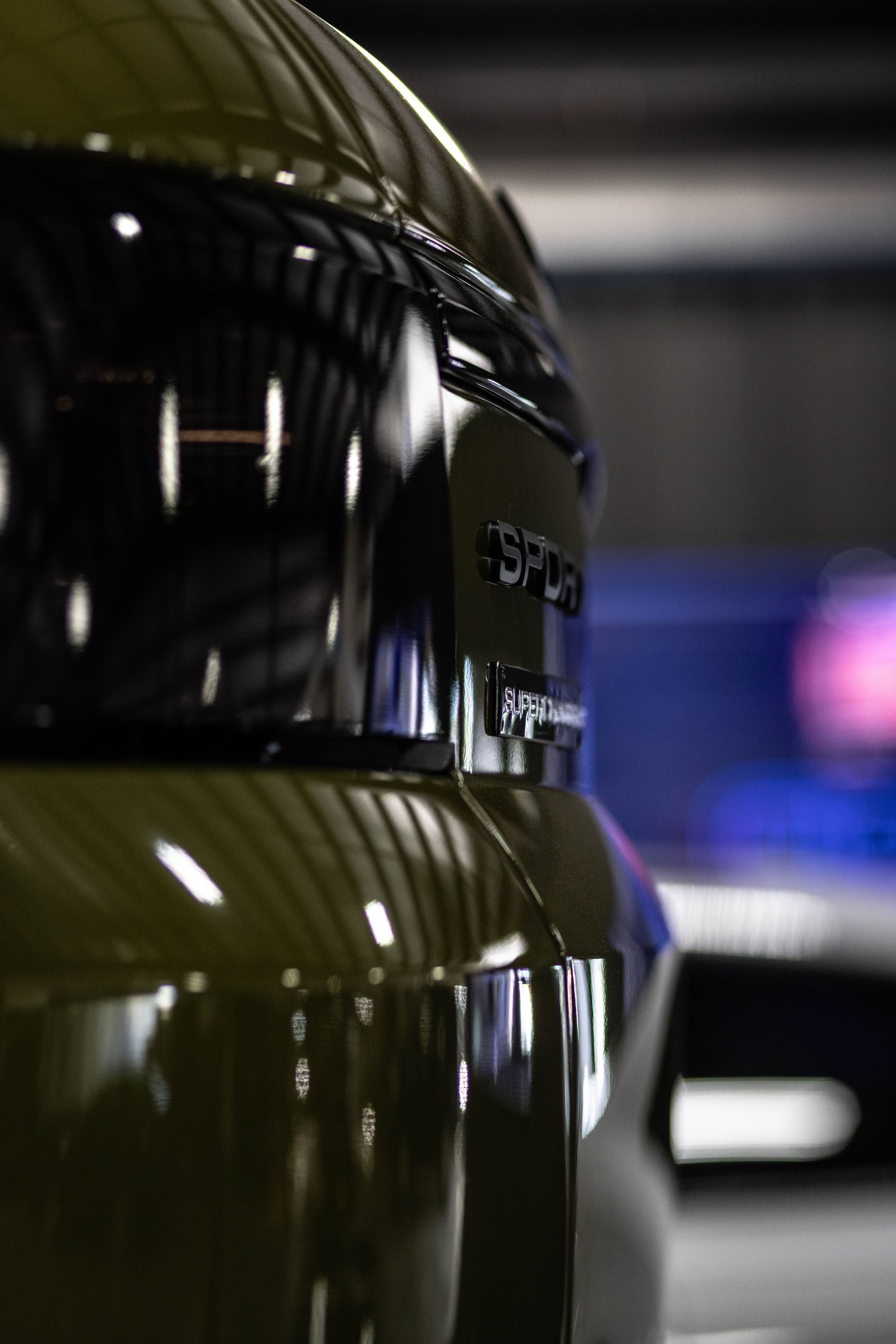 Close-up of a glossy black motorcycle helmet with green stripes, reflecting light in a garage.
