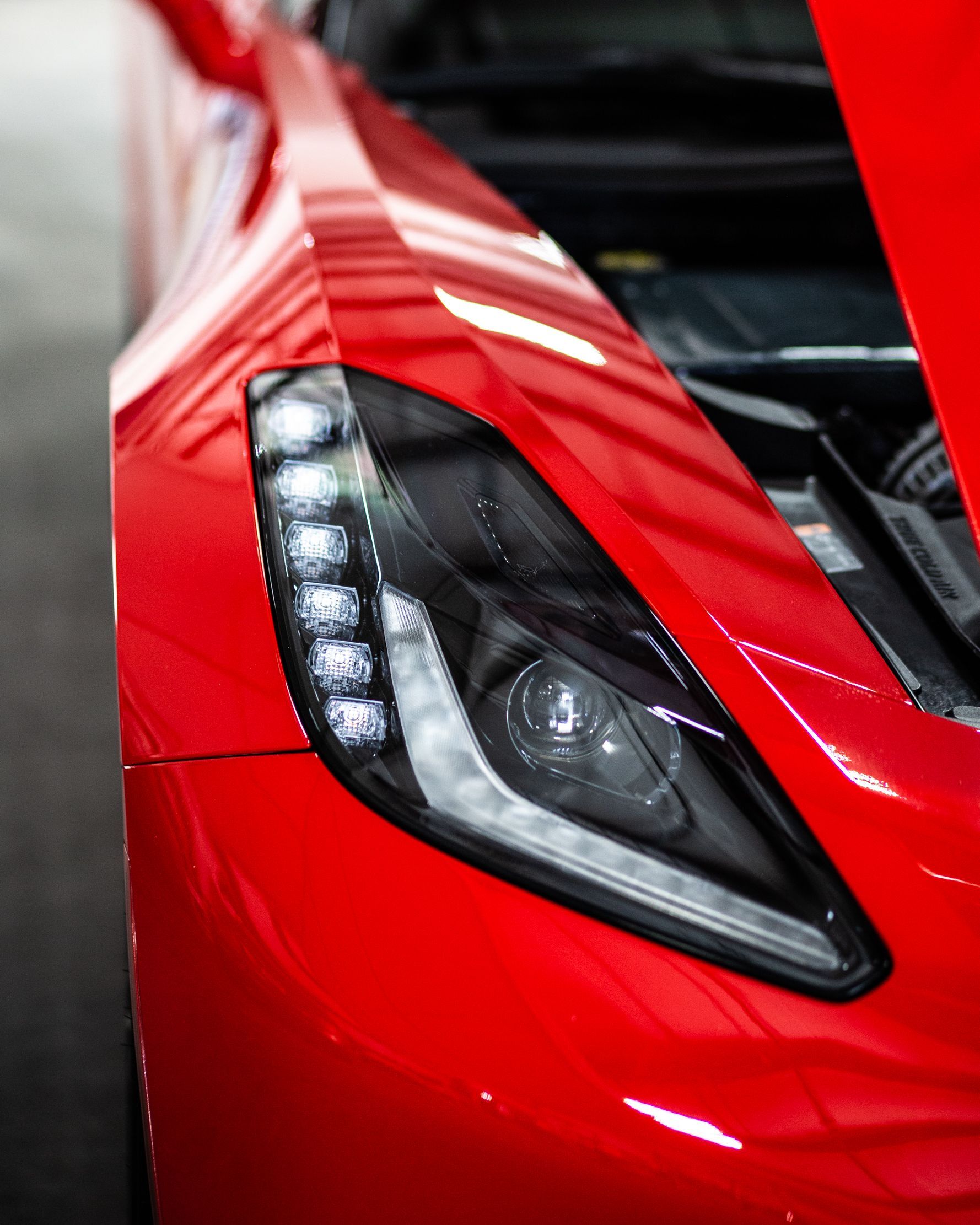 Close-up of a red sports car headlight with a glossy black housing