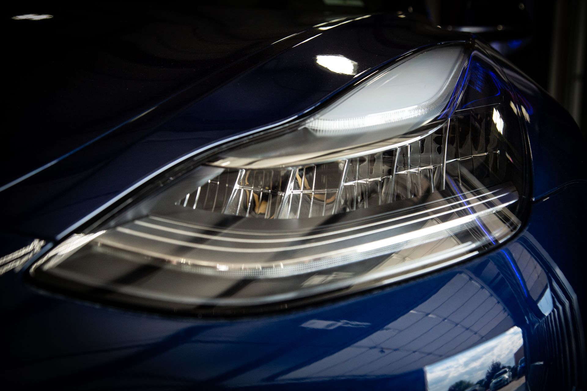 Close-up of a blue car’s front headlight with chrome detailing