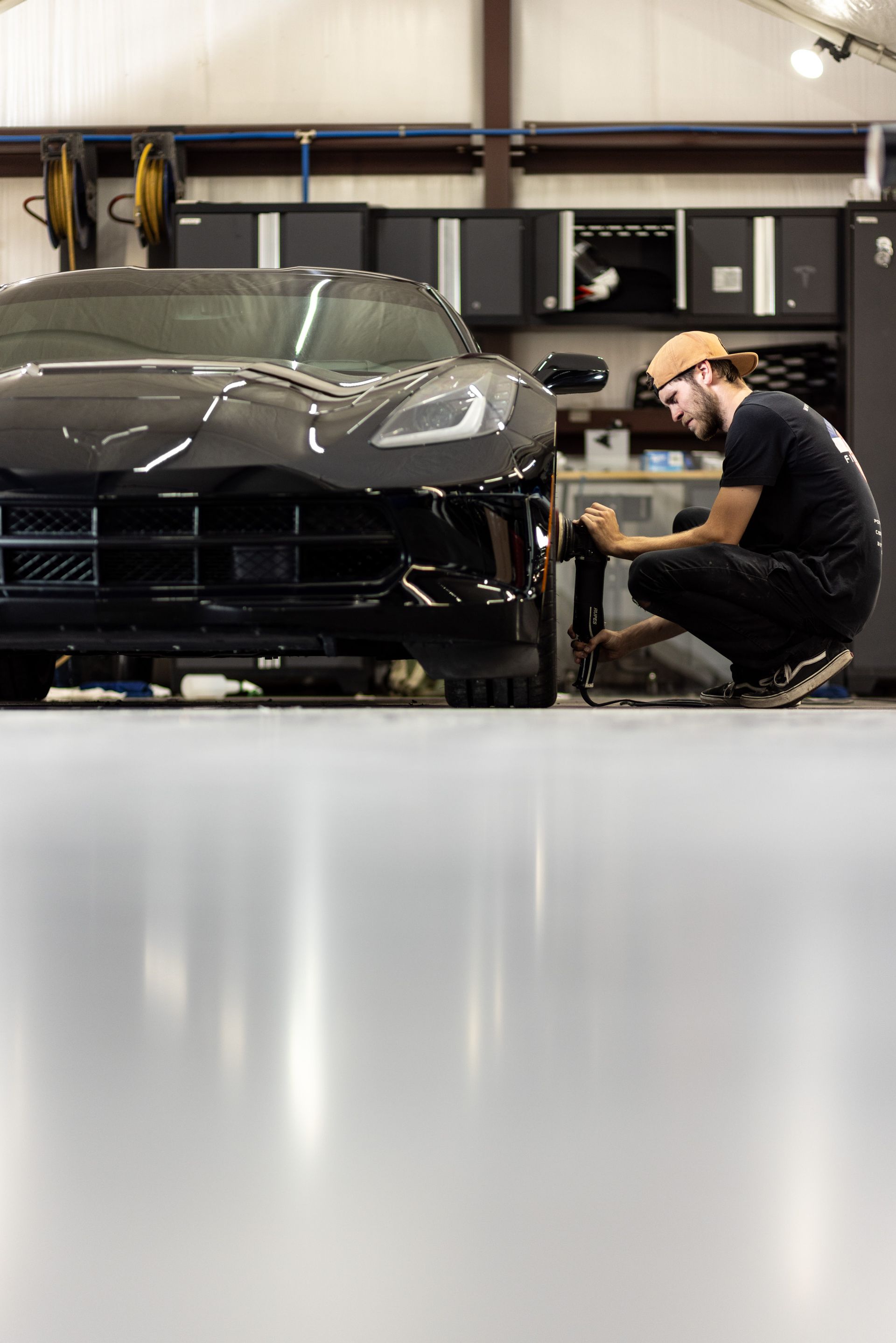 Mechanic working on a black sports car in a garage workshop