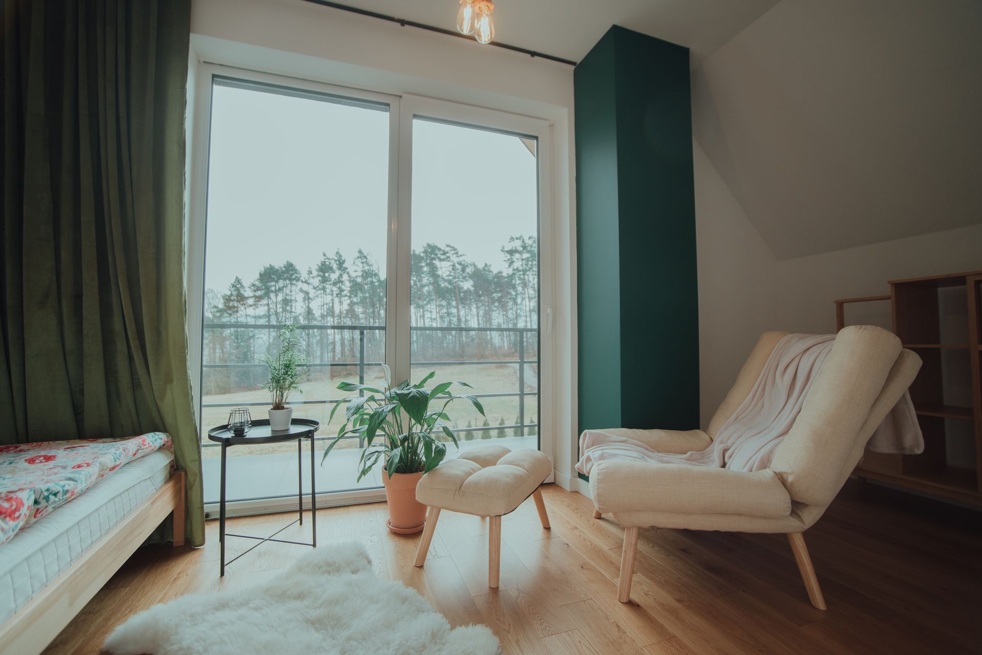 Cozy living room with a chair, plants, and a large window overlooking a snowy balcony.