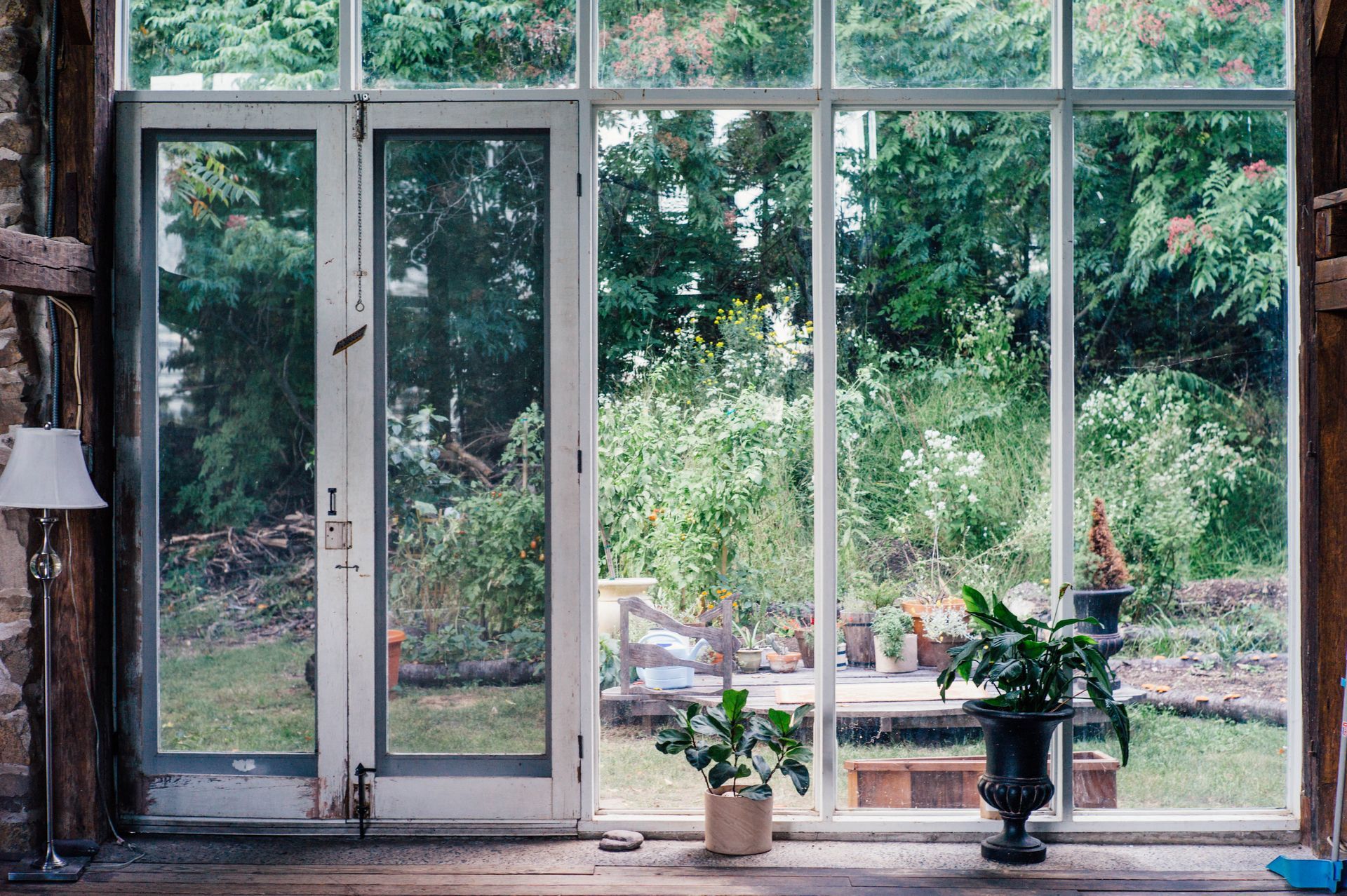 Glass patio doors open to a lush garden, with potted plants on the floor inside.