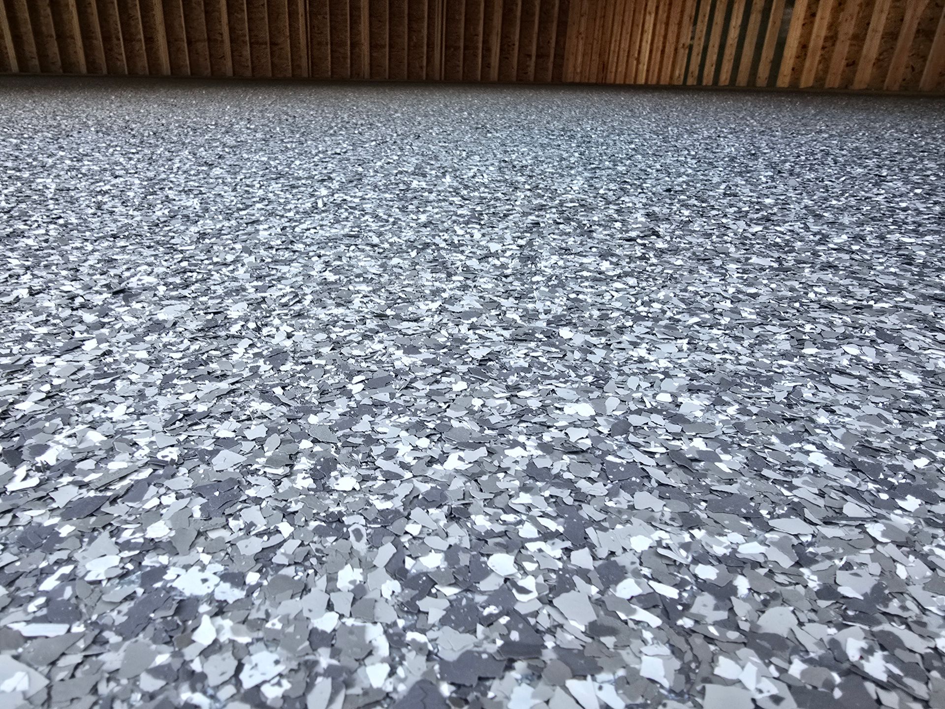 Gray and white speckled epoxy floor with wooden ceiling in the background.