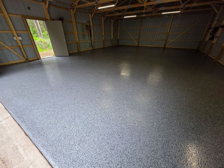 Empty garage with a speckled gray epoxy floor, open door.