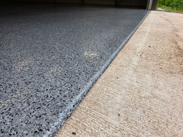 Gray speckled epoxy flooring meets concrete driveway.