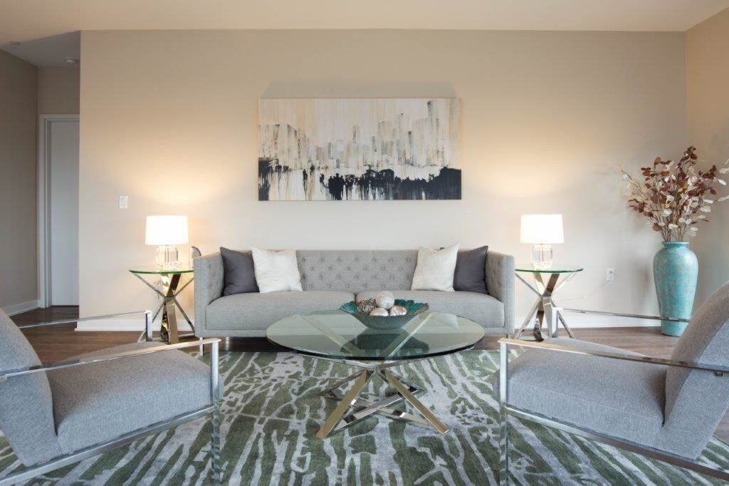 Modern living room with gray sofa, abstract wall art, lamps, and teal rug