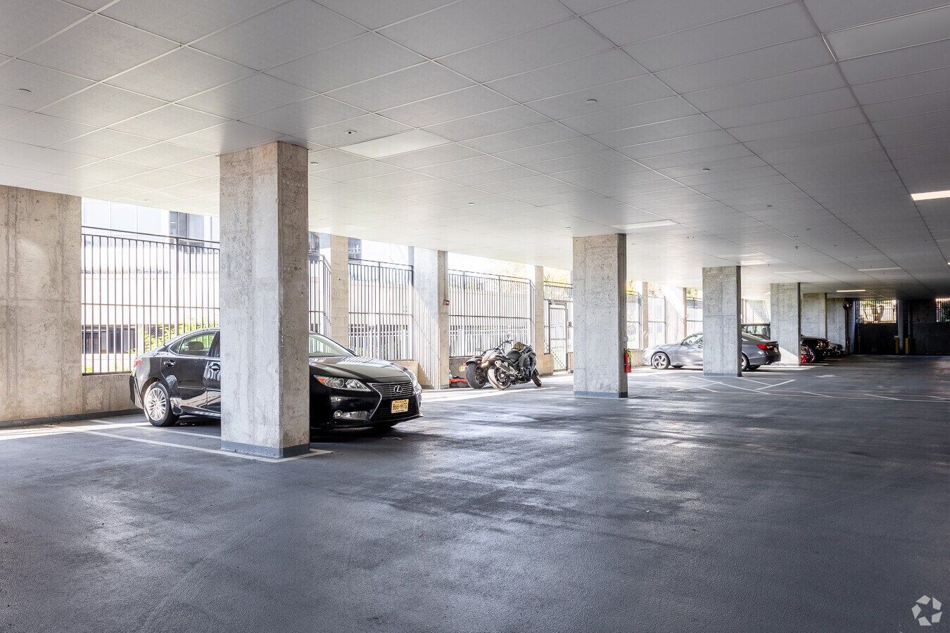 Empty covered parking garage with concrete columns and a few parked cars