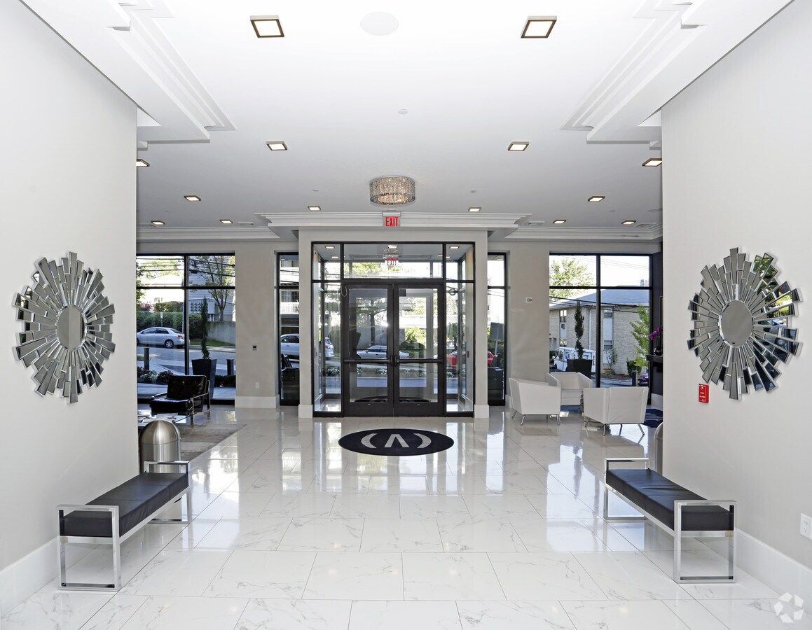 Bright modern lobby with glass doors, white walls, glossy floor, and benches on both sides