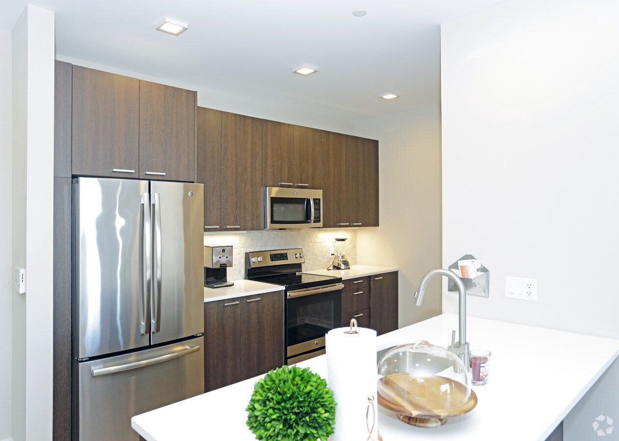 Modern kitchen with stainless steel appliances, wood cabinets, and a white island countertop