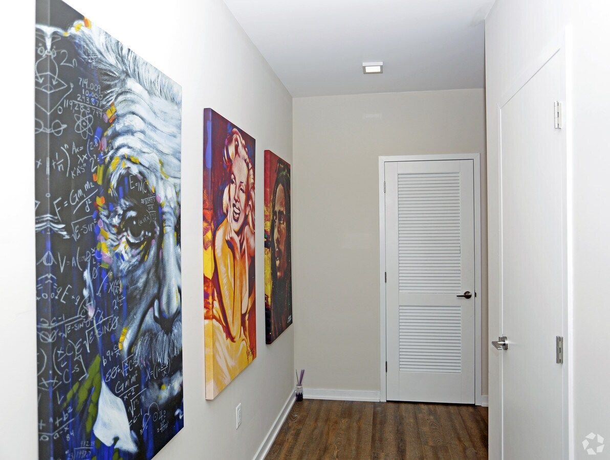 Narrow hallway with colorful abstract wall art, white doors, and wood flooring