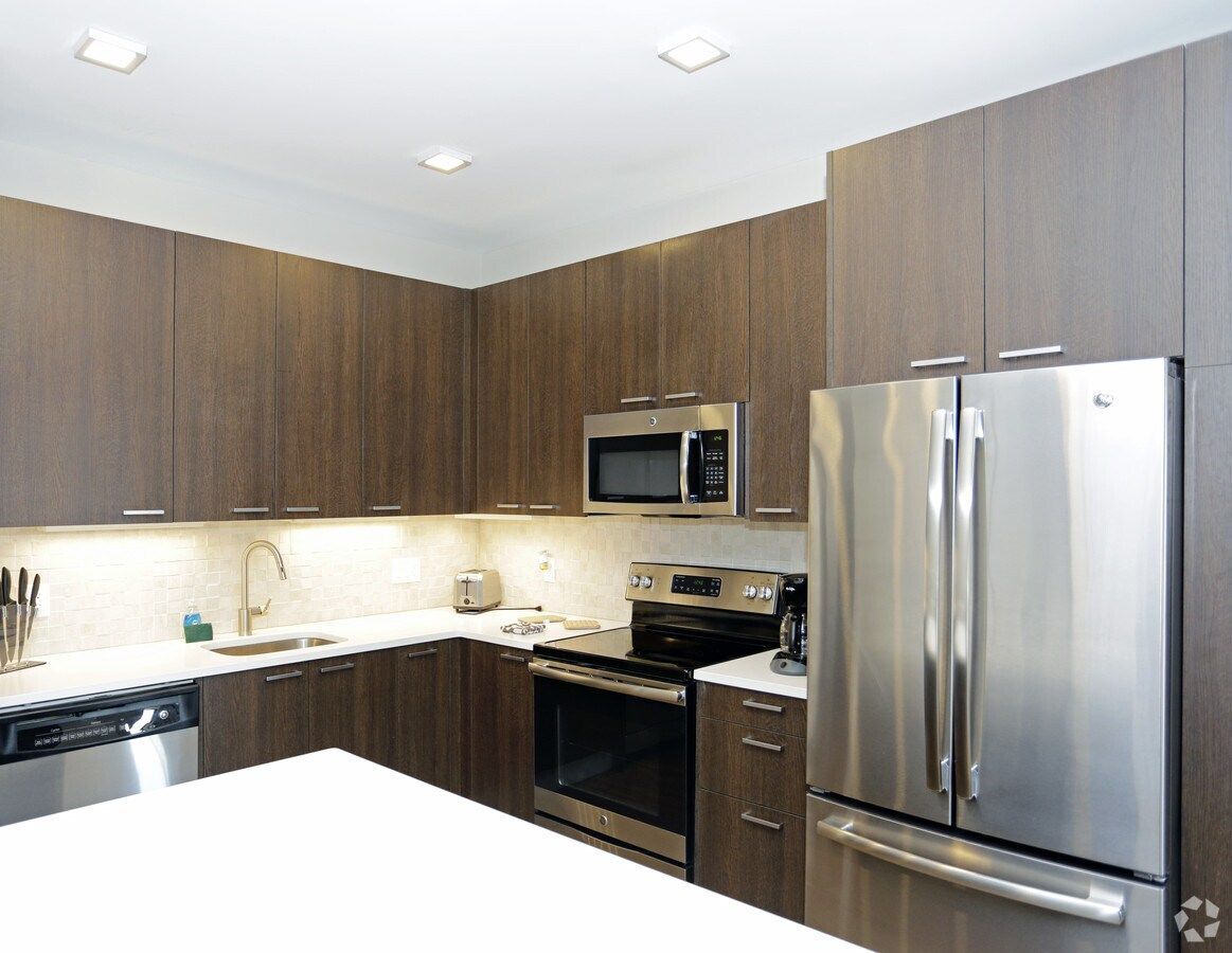 Modern kitchen with dark wood cabinets, stainless steel appliances, and a white island countertop