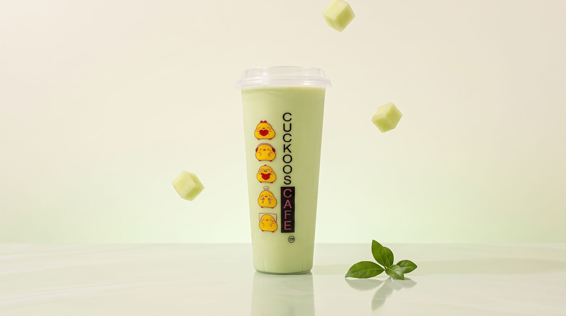 Green bubble tea cup with lemon icons, floating cubes, and mint leaves on a light background