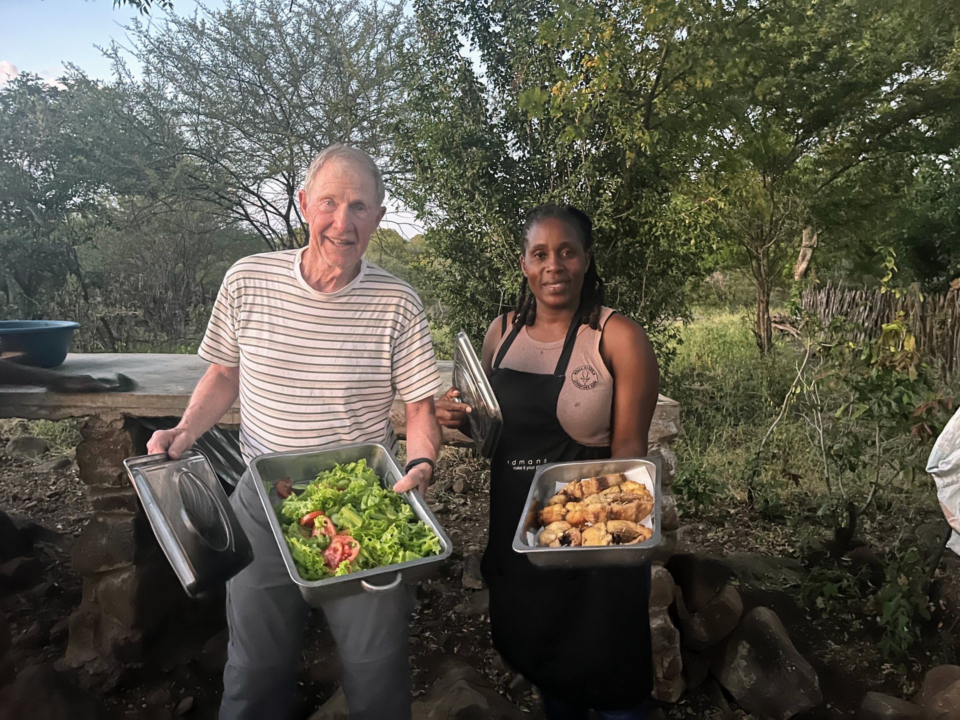 A man and a woman are holding trays of food.