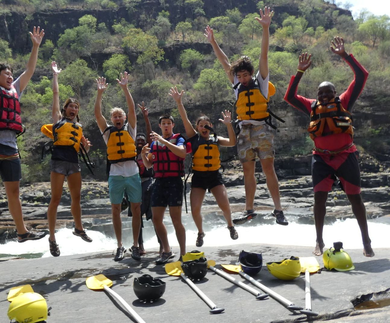 A group of people wearing life jackets are jumping in the air