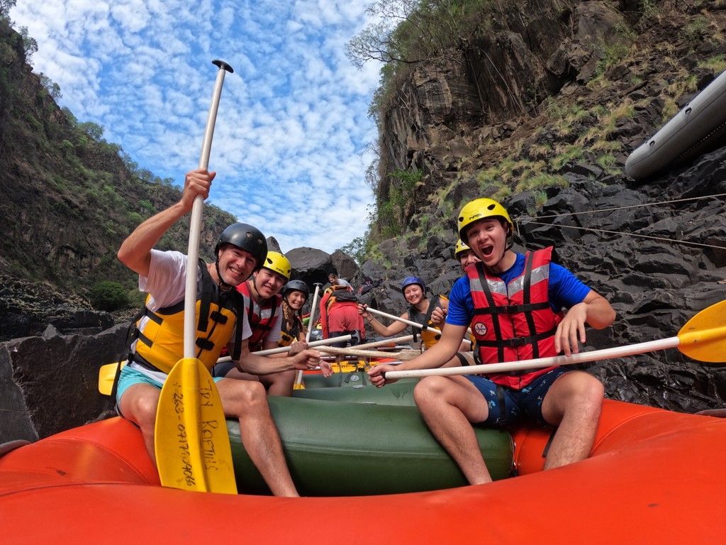 A group of people are rowing a raft down a river.