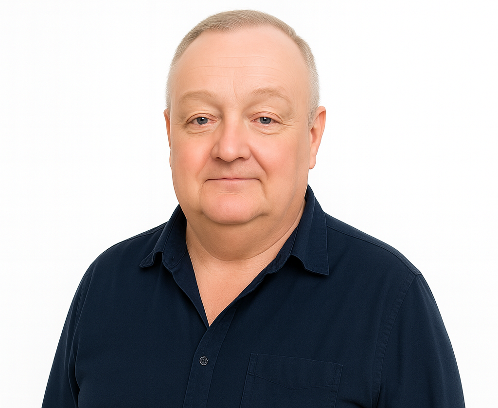 A person with short, light hair wearing a dark blue button-down shirt, looking directly at the camera against a white background.