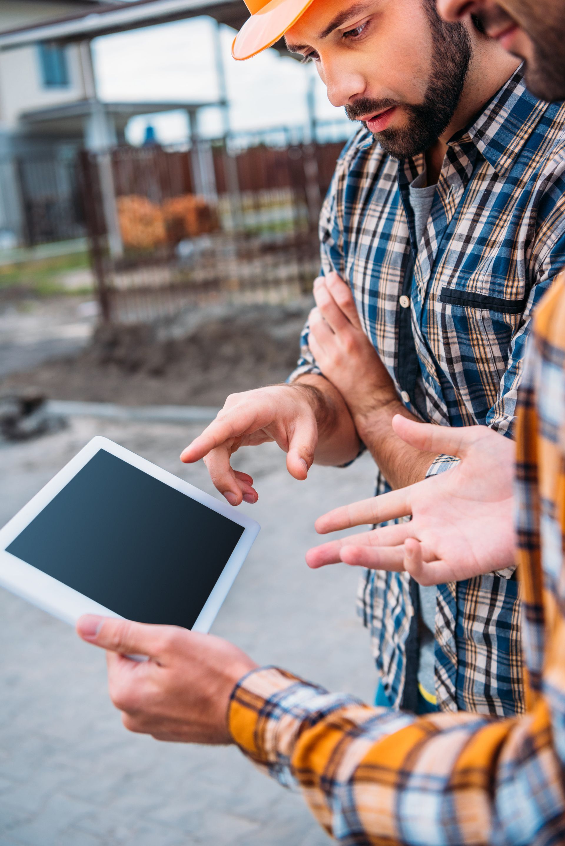 Two construction workers discuss a tablet at a building site