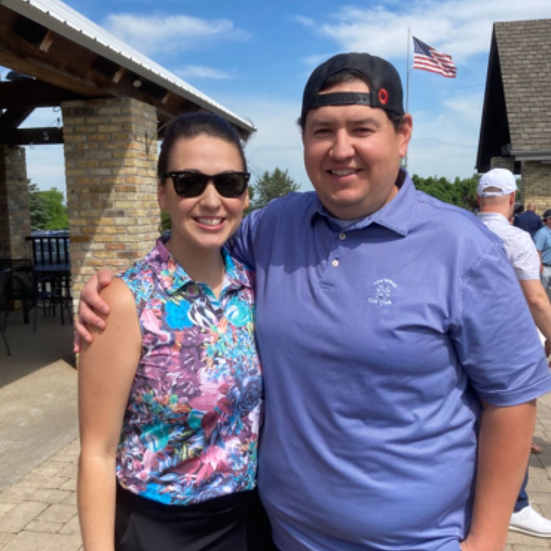 a man and a woman pose for a picture with a flag in the background