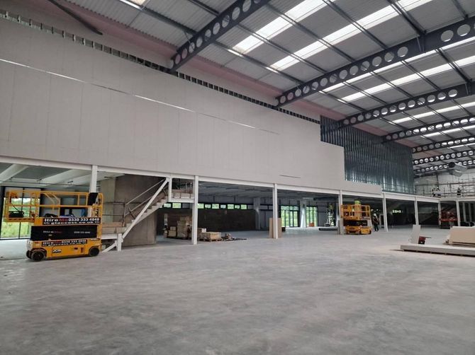 Spacious warehouse interior with yellow construction vehicles and an open concrete floor