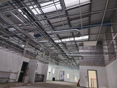 Bare unfinished interior with exposed ceiling ducts, white walls, and open doorways under construction.