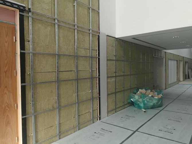 Construction site hallway with boarded walls and a pile of green trash bags on the floor