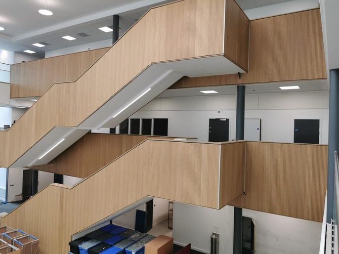 Interior stairway with wood-paneled walls and metal railings in a modern office building