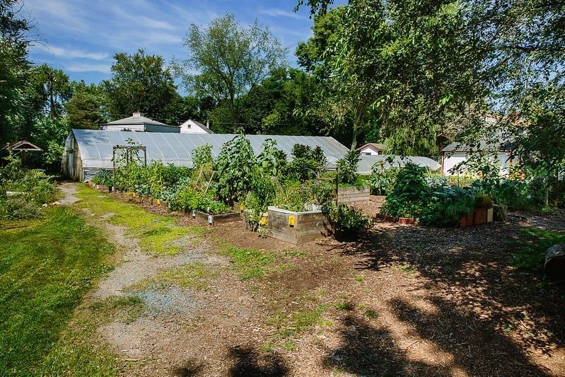 A large greenhouse is surrounded by a lush green garden.