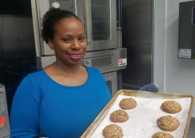 A woman in a blue shirt is holding a tray of cookies.