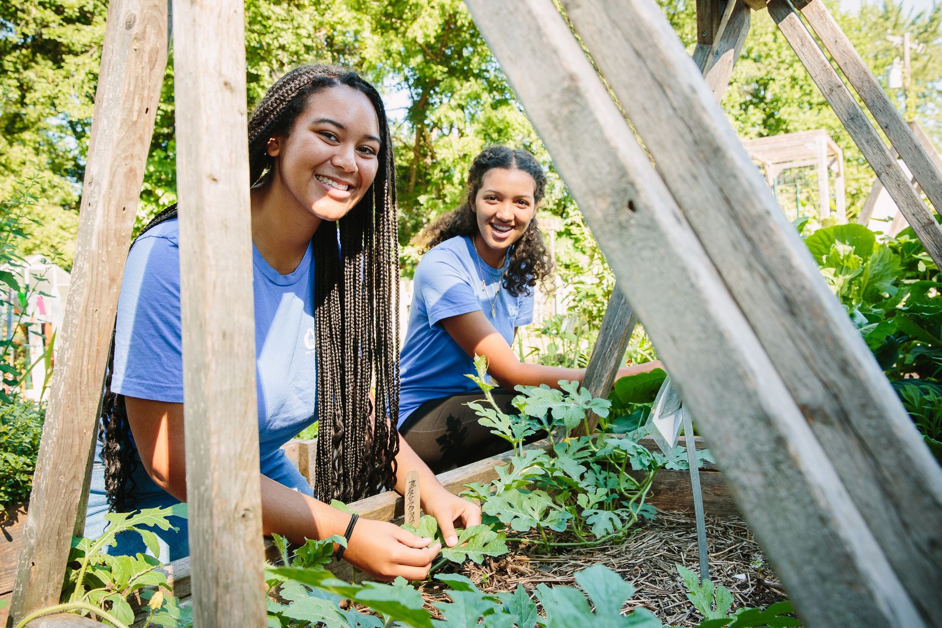 Two young women are working in a garden.