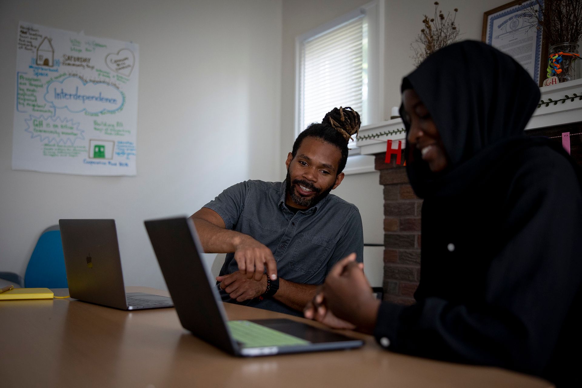 A man and a woman are sitting at a table with laptops.