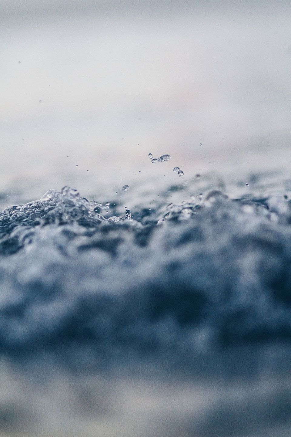 Close-up of water splashing, with blurred blue-gray waves in the foreground.