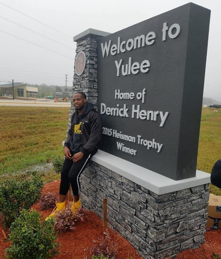 Picture of Derrick Henry standing in front of the Welcome to Yulee sign