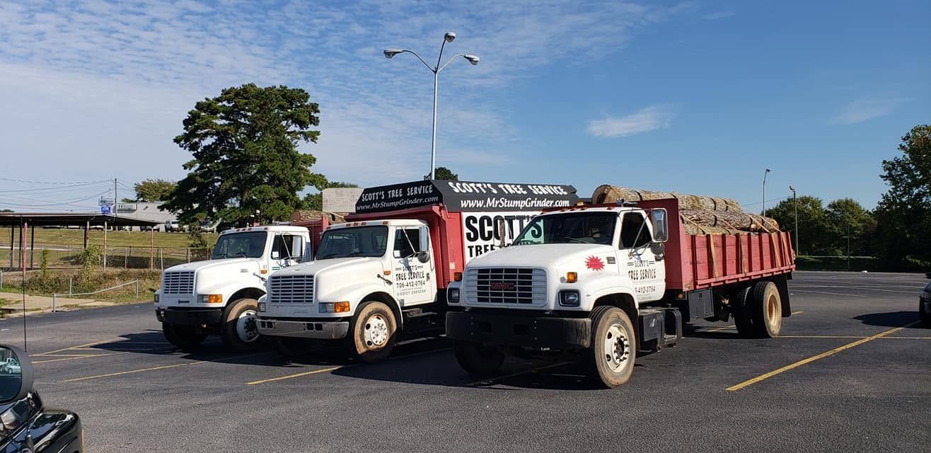 White tow truck hauling a red dump trailer in an empty parking lot under a blue sky