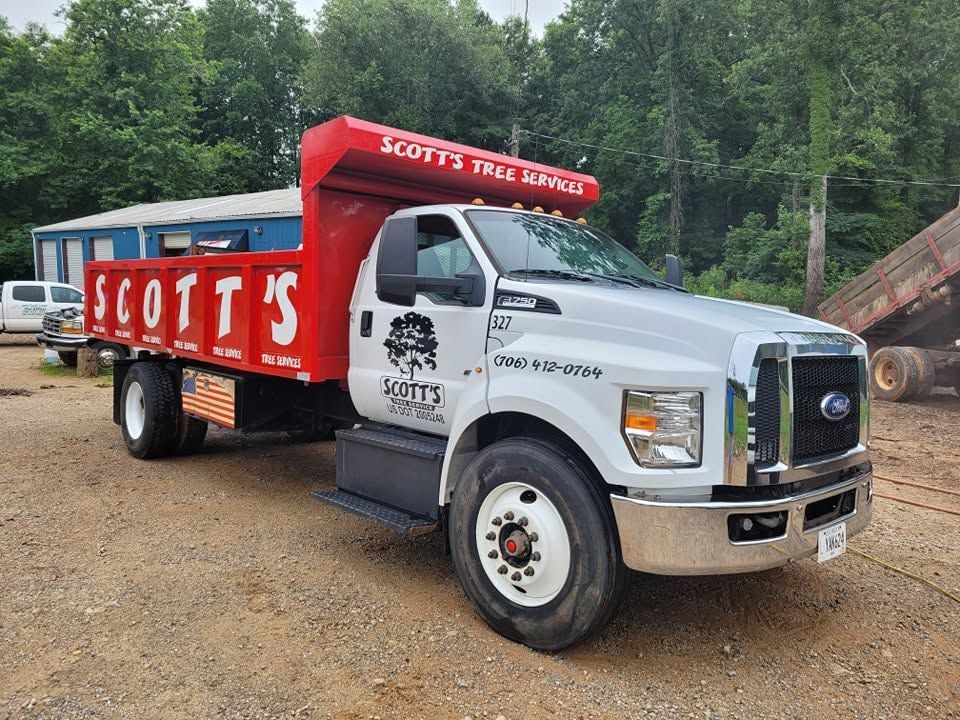 White Scott’s Tree Service truck with red trailer parked on gravel near trees