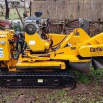Yellow stump grinder on tracks, outdoors. 
