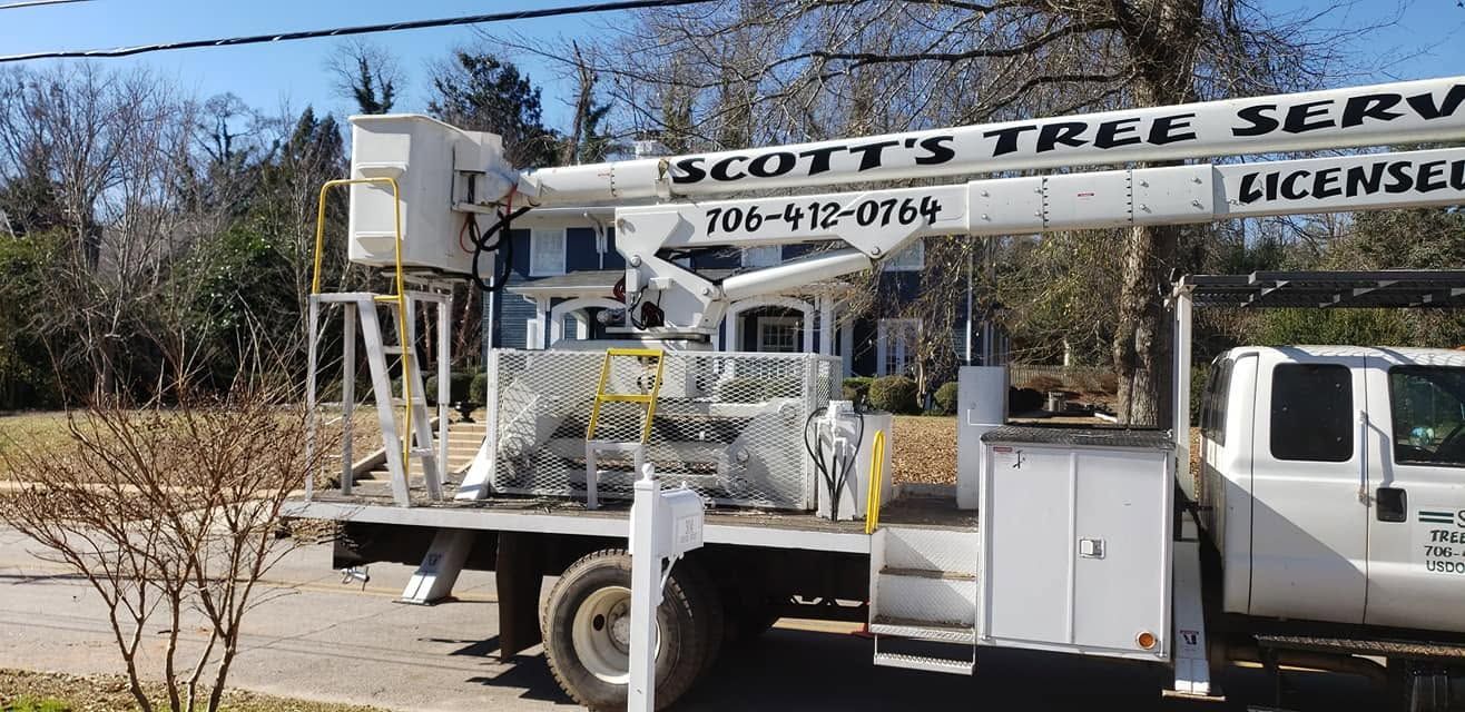 Tree service bucket truck with lift parked outdoors beside a white utility truck