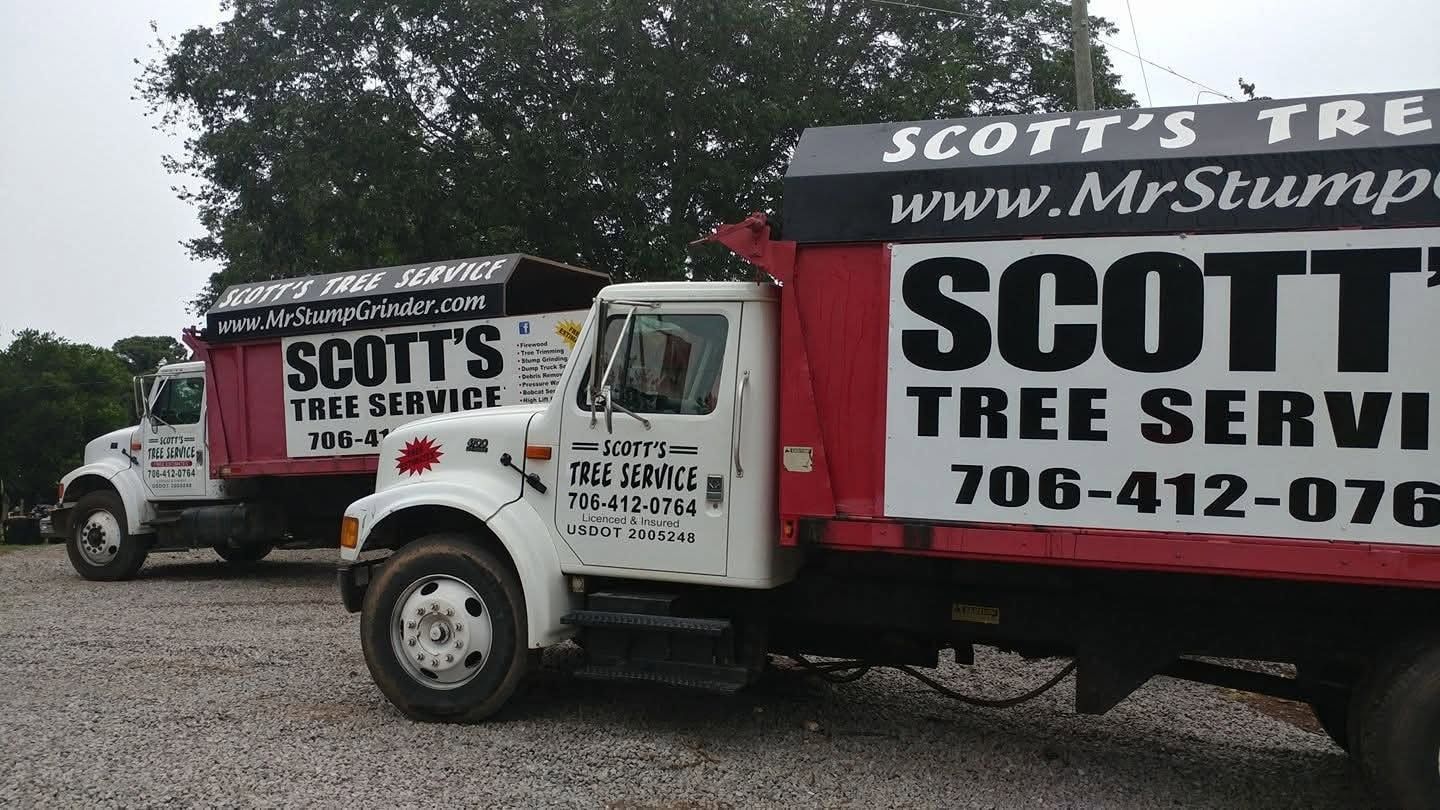 Two Scott’s Tree Service trucks parked on a gravel lot, with large company logos and phone number visible