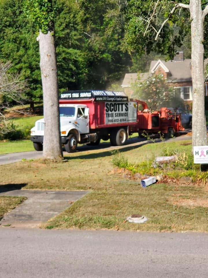 White work truck towing red landscaping equipment along a suburban street with trees and homes nearby