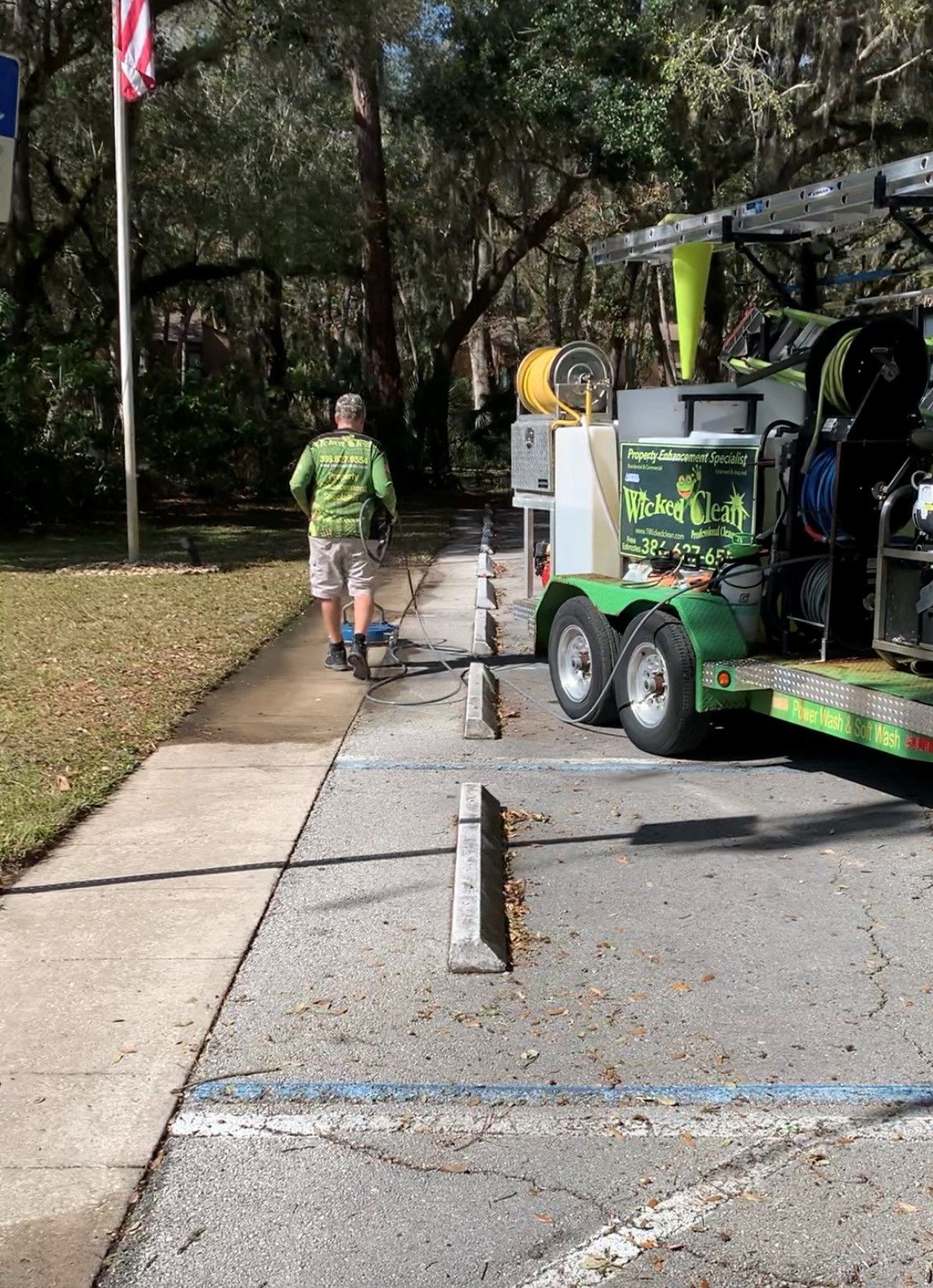 Technician power washing a concrete surface with overlapping wash lines