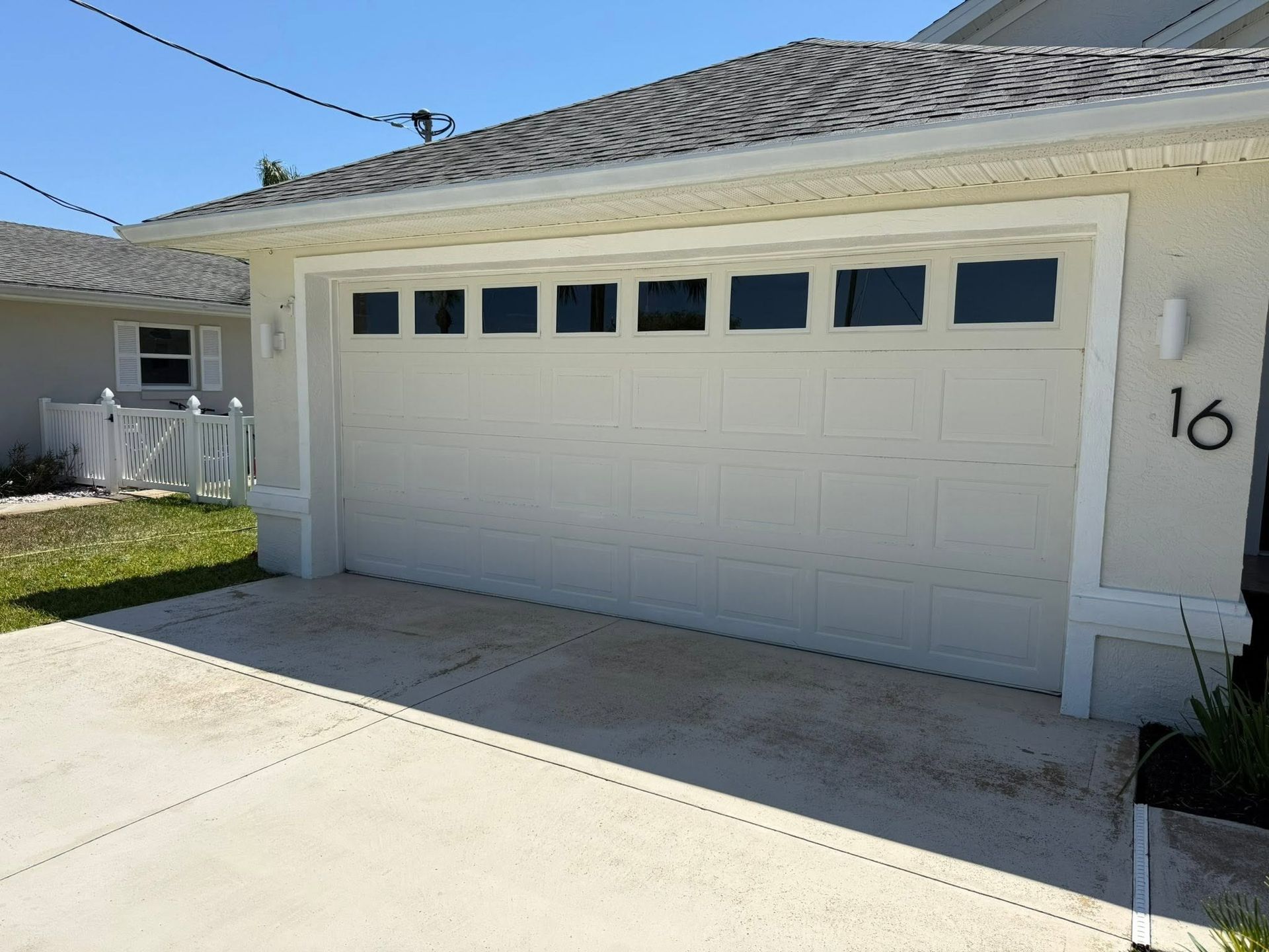 White two-car garage with small windows and driveway in front of a house