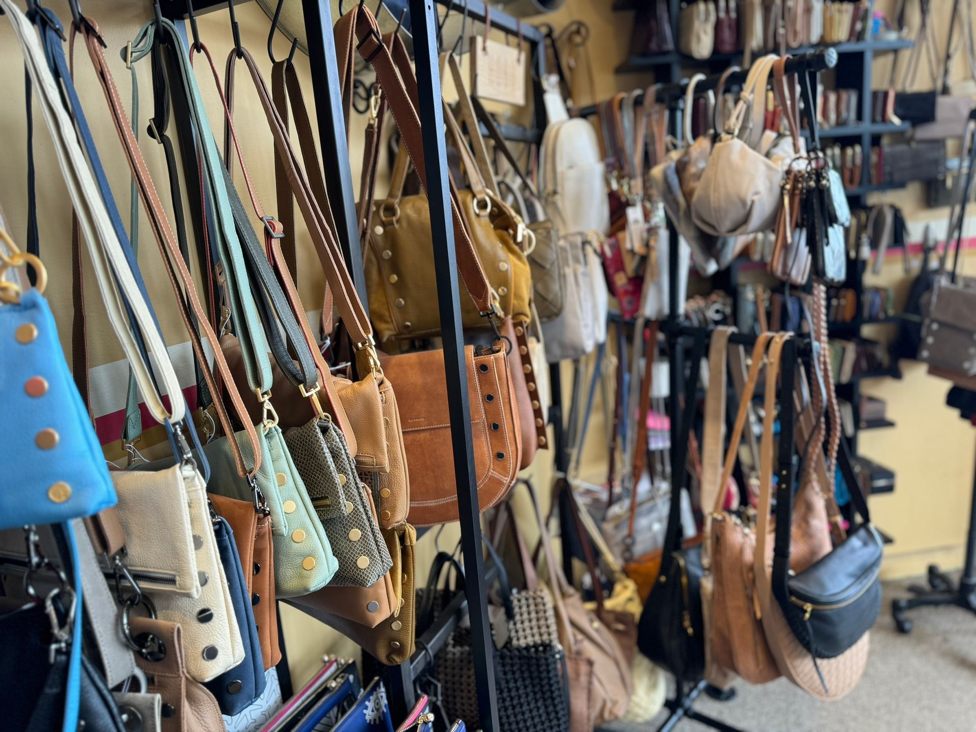 A bunch of handbags are hanging on a rack in a store.