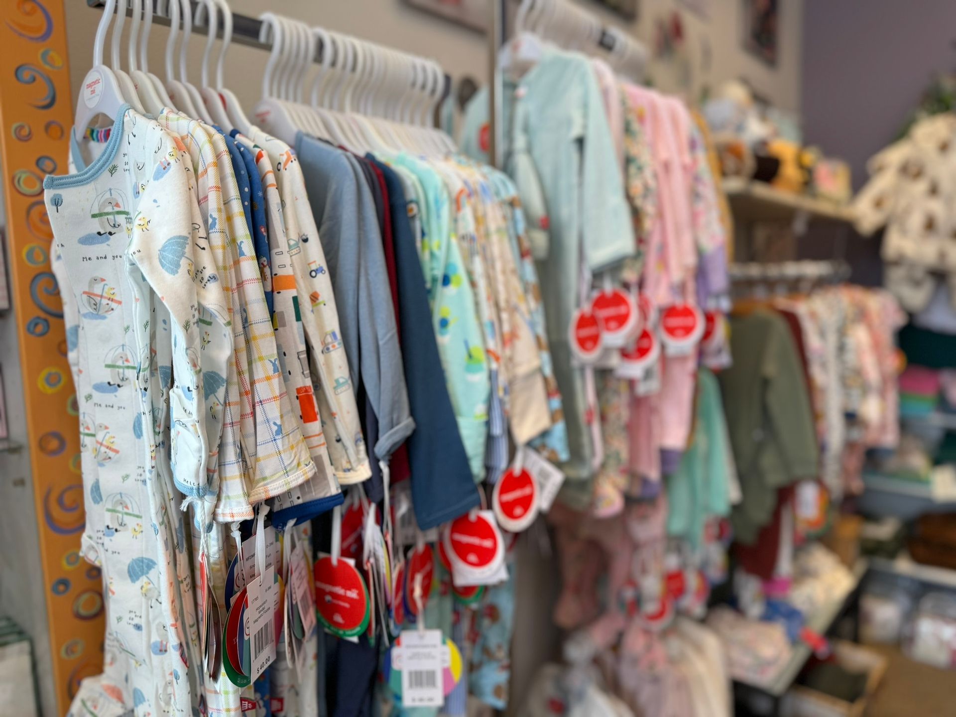 A bunch of baby clothes are hanging on a rack in a store.