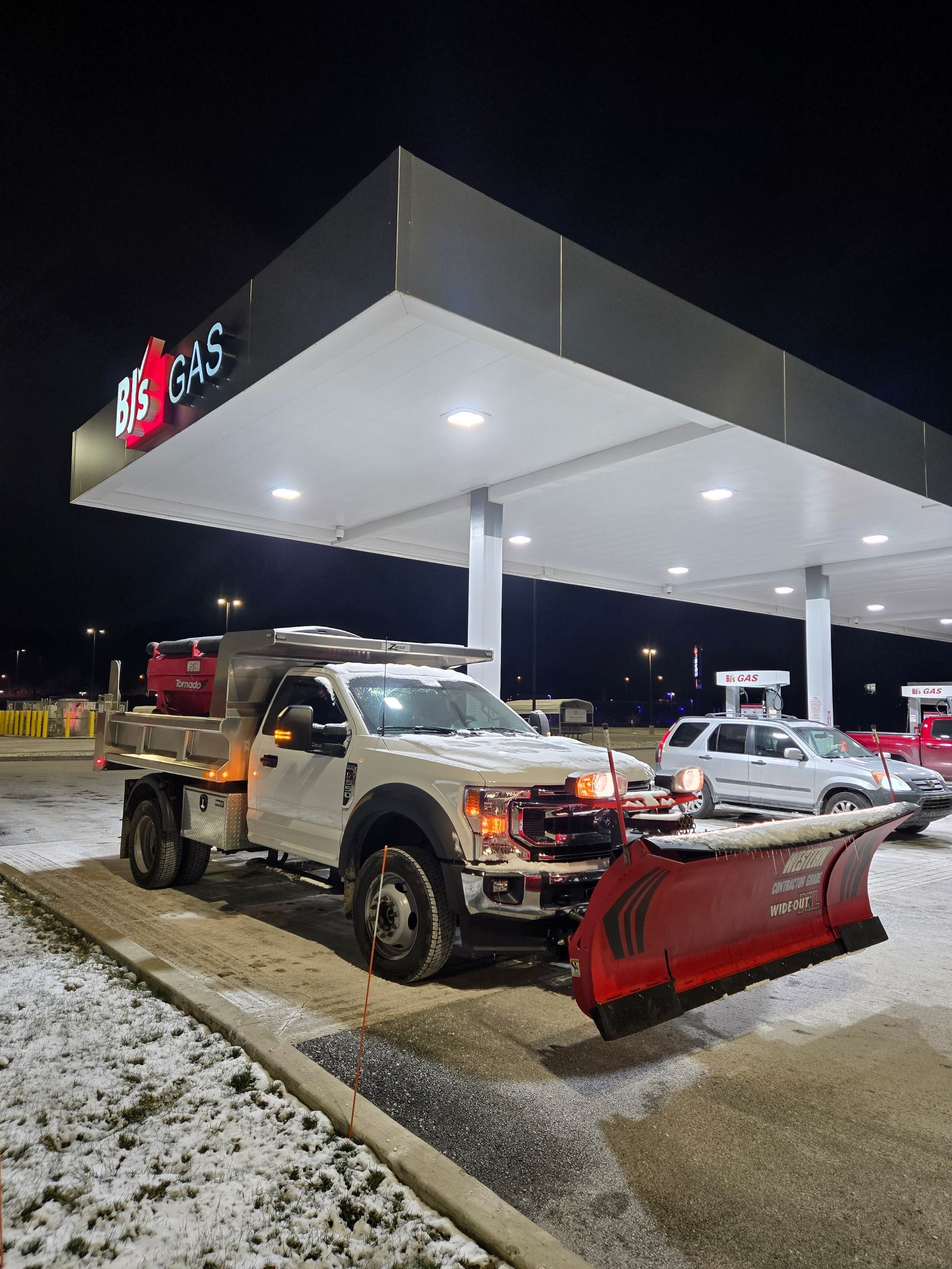 A snow plow is parked in front of a gas station at night — Bridgeville, PA — MC Landscaping