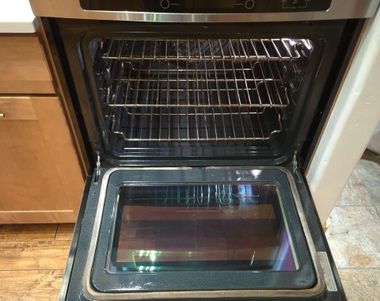 Open oven door with empty racks and a glass-fronted door in a kitchen
