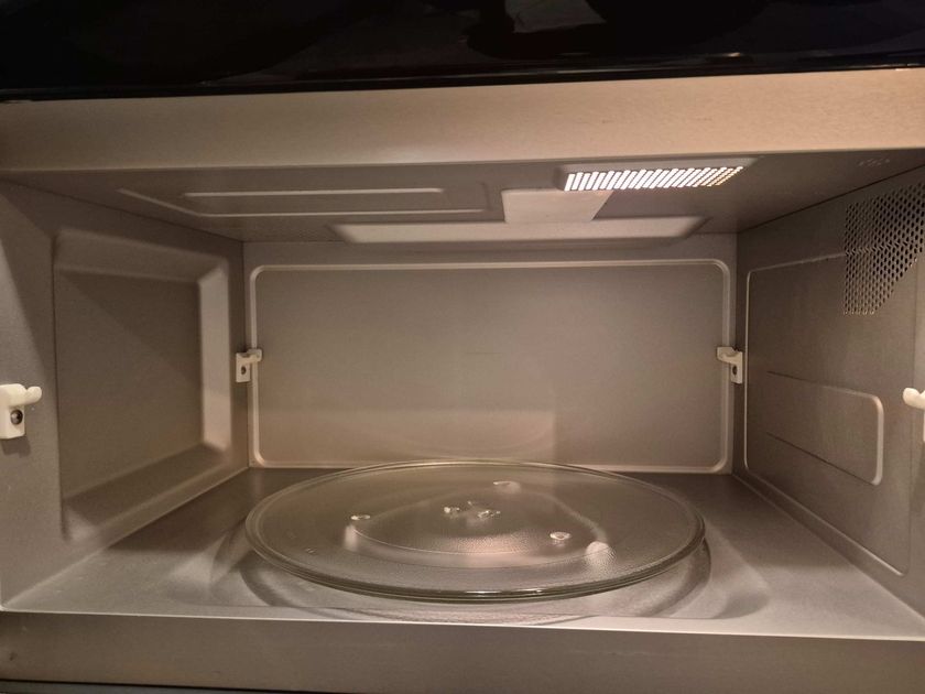 Inside of a microwave with a glass turntable and empty gray interior.